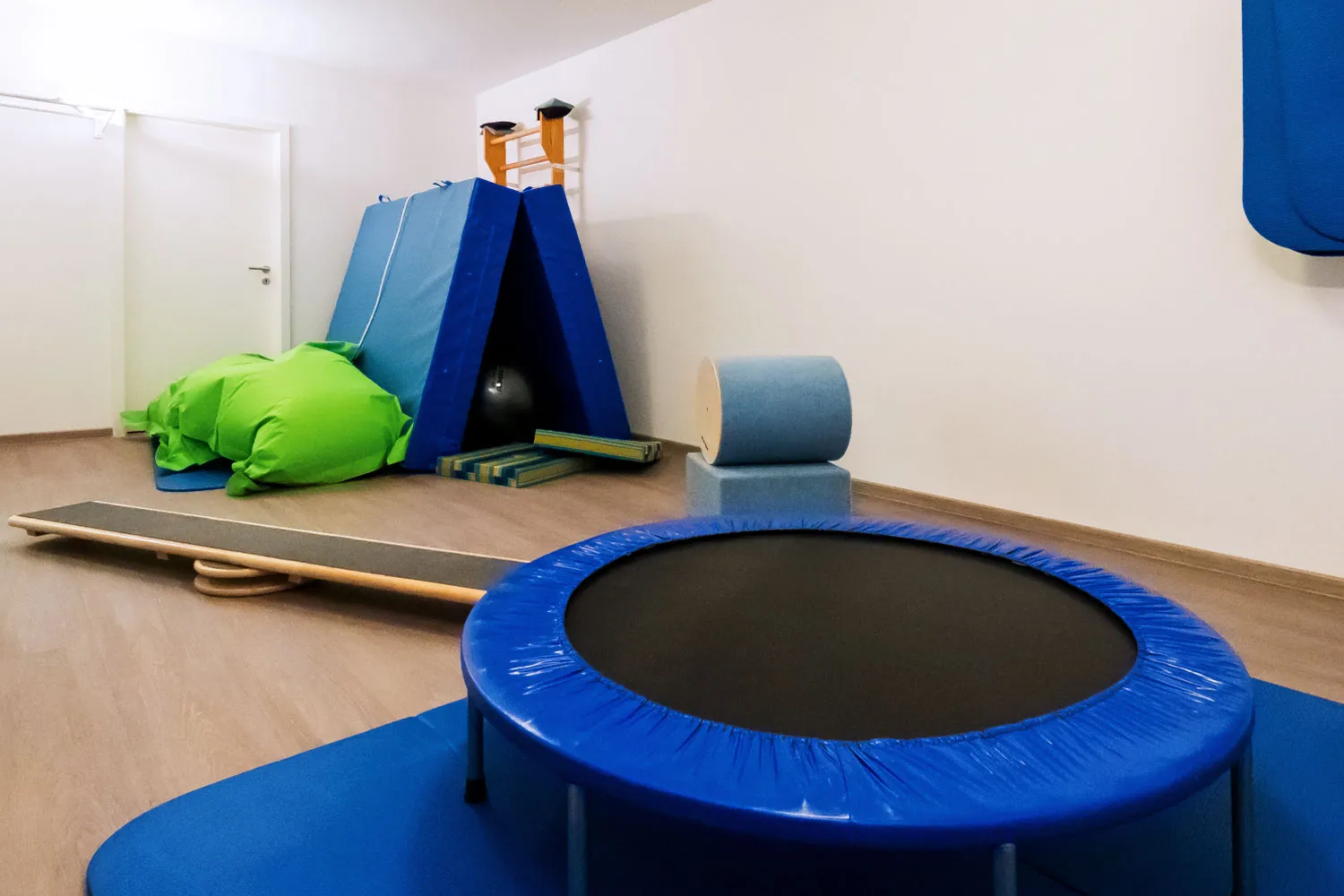 Heller Bewegungsraum der Ergotherapie-Praxis mit Trampolin, Kletterwand und Weichbodenmatten